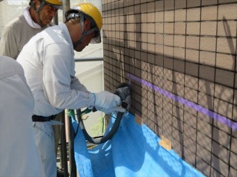 外壁タイルの目地はサンダーを使って切断していくが、集塵機で粉塵を吸いながら進める