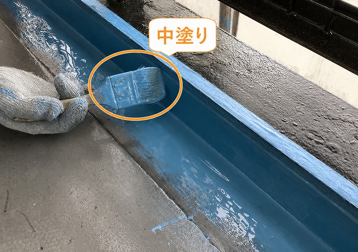 集合住宅のベランダ防水工事で中塗りしている様子