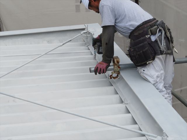 吊り金具で折板屋根の上から吊り下げられている軒樋を下げるには屋根上のナットを緩めなければならない