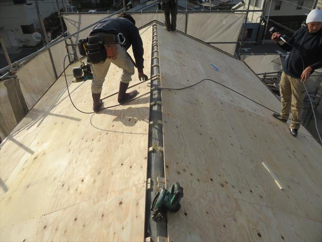 切妻屋根の両側の屋根面で軒先から張り上がっていくとき、下地の胴縁の位置を明確にしておき、必ず胴縁と垂木に釘を効かせます。 ９１０ｍｍ幅の構造用合板には、４本以上の釘で打設しますが、その本数を倍程度に増やしておきます。