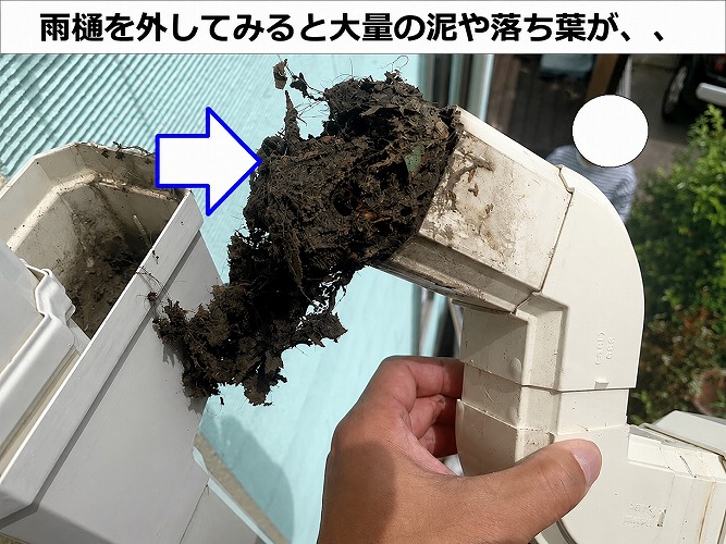 水漏れしている雨樋に大量の泥や落ち葉が詰まっている様子