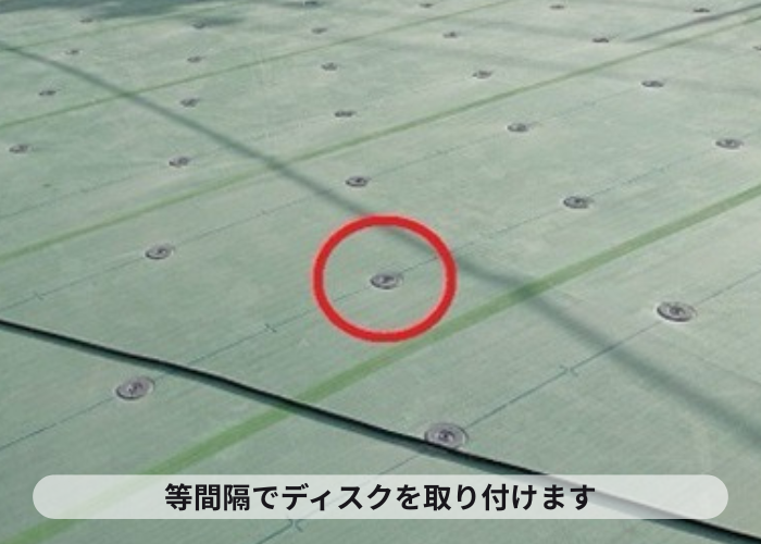尼崎市　マンション屋上防水工事の塩ビシート機械固定工法でディスクを取り付けている様子