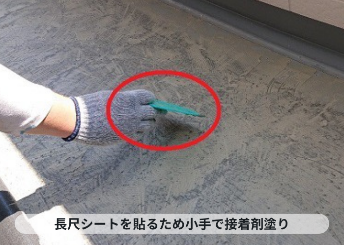 加西市　共用廊下への長尺シート貼りで接着剤を塗っている様子