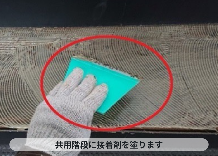 西宮市　4階建てハイツの共用階段に接着剤を塗っている様子