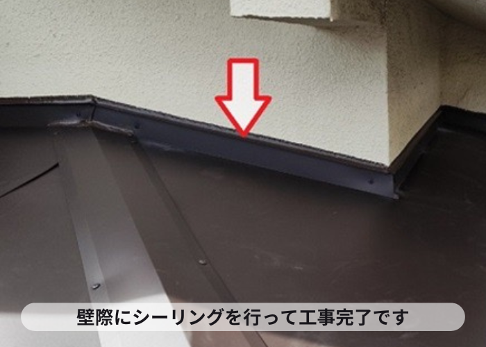 宝塚市　玄関屋根への板金工事で壁際にシーリングをしている様子