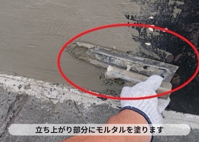 尼崎市　マンションの屋上防水工事で立ち上がり部分をモルタルで扱いている様子