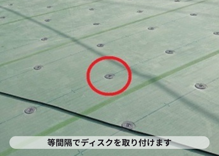 尼崎市　マンション屋上防水工事の塩ビシート機械固定工法でディスクを取り付けている様子