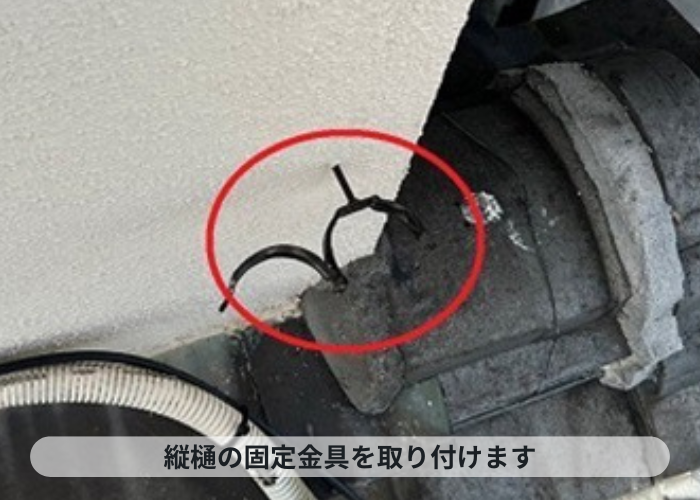 尼崎市　雨樋交換で竪樋の固定金具を取り付けている様子