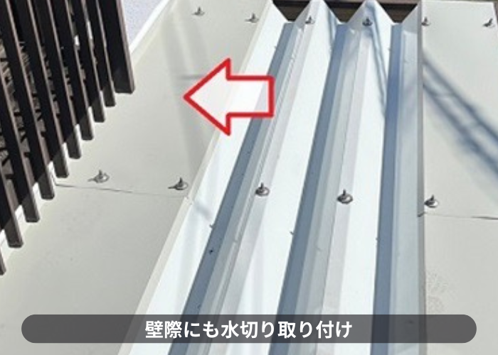 伊丹市　雨漏りを解消するための折板屋根カバー工事で壁際に雨押え水切りを取り付けている様子