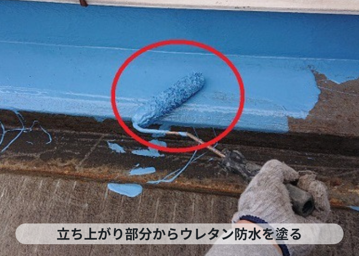 神戸市中央区　神戸市中央区の陸屋根防水工事で立ち上がり部分にウレタン防水を塗っている様子