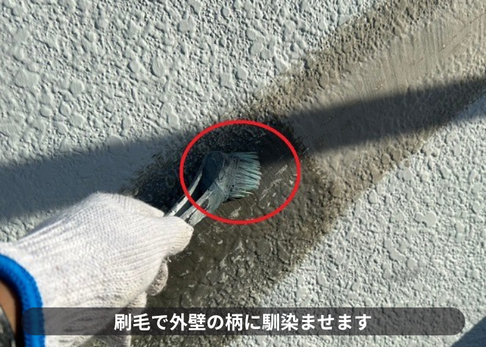 西宮市　外壁ひび割れ補修としてUカットシール工法でセメントを刷毛で馴染ませている様子