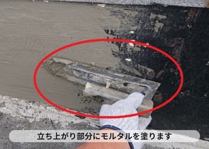 尼崎市　マンションの屋上防水工事で立ち上がり部分をモルタルで扱いている様子