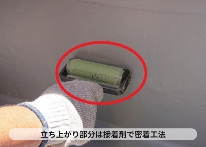 尼崎市　陸屋根防水工事で立ち上がり部分に塩ビシートを貼っている様子