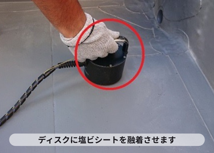 尼崎市　陸屋根防水工事で塩ビシートを下地のディスクに融着させている様子