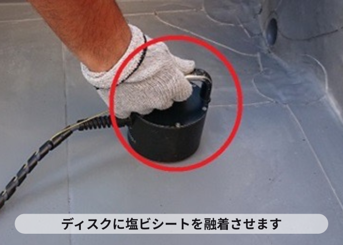 尼崎市　陸屋根防水工事で塩ビシートを下地のディスクに融着させている様子